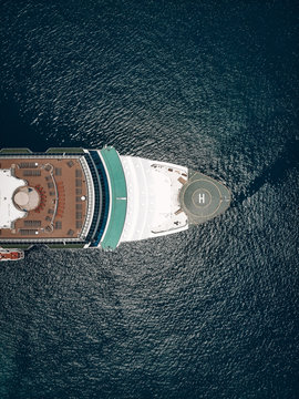 Drone view of the of the cruise liner, red-brick deck, helideck and deck-chairs, blue sunny sea with flecks around. Vessel equipment concept.