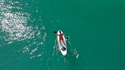 Fototapeta premium Aerial drone photo of man exercising sup paddle board in tropical exotic lake with emerald waters