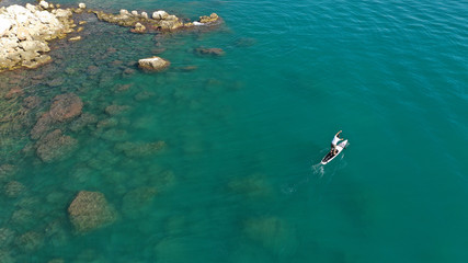 Aerial drone photo of man exercising sup paddle board in tropical exotic lake with emerald waters