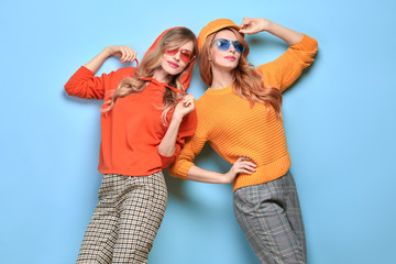 Two easy-going happy hipster Woman smiling in Stylish fashion orange colored outfit. Beautiful Girl...