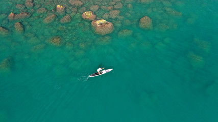 Aerial drone photo of man exercising sup paddle board in tropical exotic lake with emerald waters