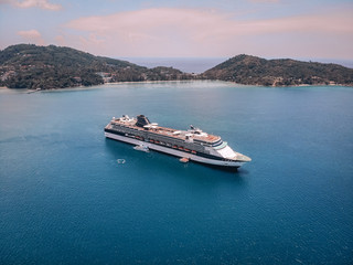 Bird eye view of the amazing white cruise ship sailing by the islands, blue ocean, horizon; luxurious tour concept.