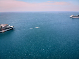 Fototapeta premium Drone shot of the snout of the cruise ships in a voyage by sea, boats nearby; horizon, vast blue waters.