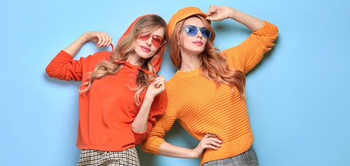 Two easy-going happy hipster Woman smiling in Stylish fashion orange colored outfit. Beautiful Girl in Trendy sweatshirt, cap. Joyful sister, friend, Creative fashionable friendship concept