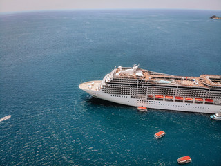Top view of the huge white liner heading to the lagoon, boats around it in the sea; side view shot.