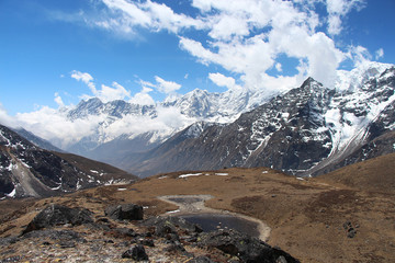 Plain with dried grass and mountain peaks in the background near Lunden village in the Himalayas in Nepal. Sagarmatha national park, route to the Everest base camp through Gokyo lakes.