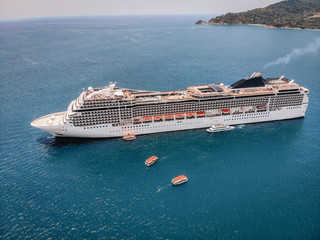 Top view of the huge white liner heading to the lagoon, boats around it in the sea; side view shot.