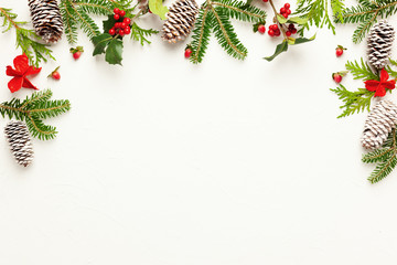 Christmas background with pine cones, branches of holly with red berries and fir tree on white....