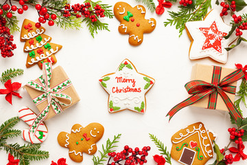Christmas background with gingerbread cookies, gift boxes and branches of holly with red berries on...