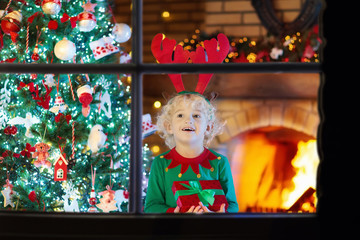 Child at Christmas tree and fireplace on Xmas eve