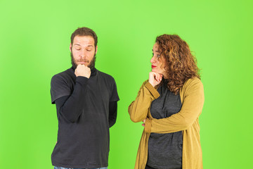 Young beautiful couple on isolated green background with hand on chin thinking about question, pensive expression. Smiling with thoughtful face. Doubt concept.