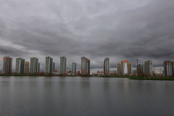 residential complex of high-rise buildings on the banks of the pond in inclement weather