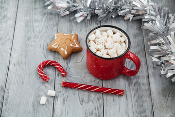 Red mag of drink with candy cane and Christmas gigerbread on wooden background. Christmas Greeting...