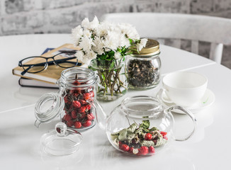 Obraz na płótnie Canvas Kitchen table with herbal rosehip tea teapot, chrysanthemum bouquet, books. Cozy lazy home still life