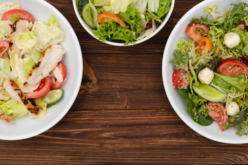 white deep plates with fresh salad ingredients mixed with sauce placed on an attractive background. A place for a menu, banner or advertisement