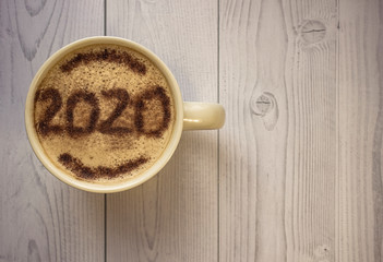 Mug of cappuccino with cinnamon for breakfast.Cinnamon powder is sprinkled with 2020 numbers on...