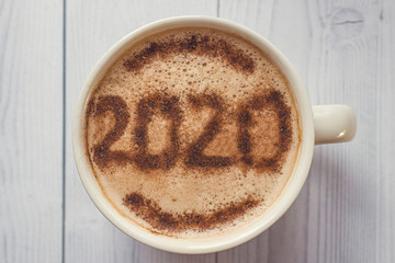 Mug of cappuccino with cinnamon for breakfast.Cinnamon powder is sprinkled with 2020 numbers on coffee foam.The symbol of the new year on the coffee foam. Morning Cup of coffee with hot cappuccino.