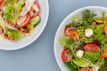 white deep plates with fresh salad ingredients mixed with sauce placed on an attractive background. A place for a menu, banner or advertisement