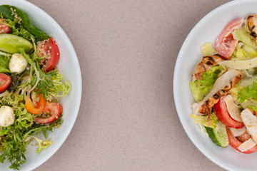 white deep plates with fresh salad ingredients mixed with sauce placed on an attractive background. A place for a menu, banner or advertisement