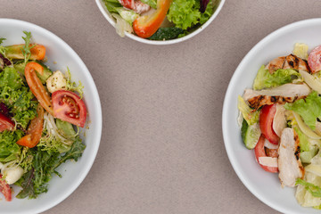 white deep plates with fresh salad ingredients mixed with sauce placed on an attractive background. A place for a menu, banner or advertisement