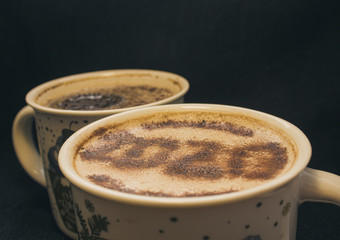 Mug of cappuccino with cinnamon for breakfast.Cinnamon powder is sprinkled with 2020 numbers on coffee foam. Cookie with a paw pattern floats in a cappuccino.Morning Cup of coffee with hot cappuccino.