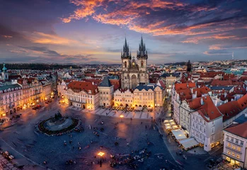 Fotobehang Uitzicht over de daken van de oude stad en het centrale plein van Praag naar de verlichte Tynkerk in de avond na zonsondergang, Tsjechië © moofushi