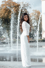 Fototapeta na wymiar Fashion gorgeous woman in beautiful dress. Luxury girl with dark long hair and nude makeup, elegant fashionable lady, vogue style female. Sexy girl near the fountain.