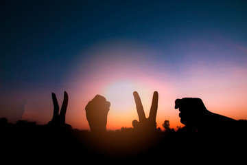 Silhouette of hands gesture V (victory) sign and fist power for victory or peace at sunset. Concept: success and winner in 2020.