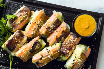 healthy vegan spring rice paper rolls with fried tofu cheese and fresh vegetables and almond sauce