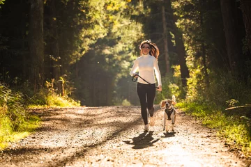 Poster Meisje loopt met een hond (Beagle) aangelijnd in de herfst, zonnige dag in het bos. Ruimte kopiëren in de natuur © Przemyslaw Iciak