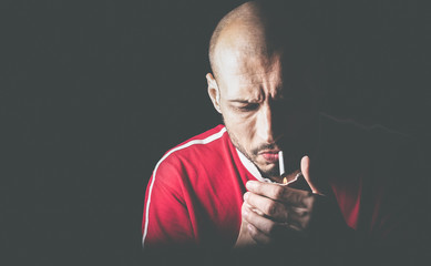Young nervous smoker man lighting up the cigarette to smoke in the dark 
