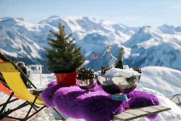 A bottle of champagne and a glass in ice on table in mountains, France