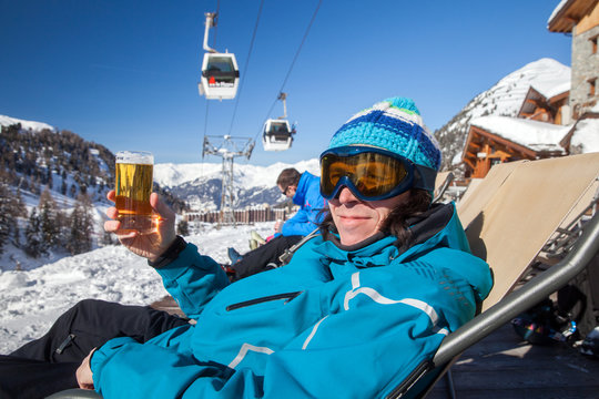 A man with glass of beer is sitting in cafe in French ski resort