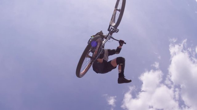 BMX Bike Back Flip Against Blue Sky And Clouds