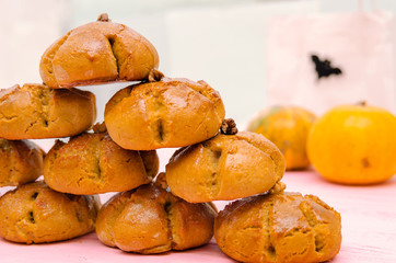 Halloween homemade buns made from pumpkin dough and whole grain flour. Halloween pumpkins on background.