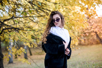 Beautiful young woman in a fur coat in the magical autumn forest.