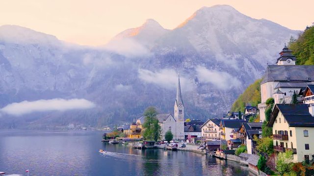Hallstatt, Austria. Beautiful sunrise scene of navigation on Hallstatter lake. Old sophisticated church abd epic clouds in background. UNESCO world heritage site.