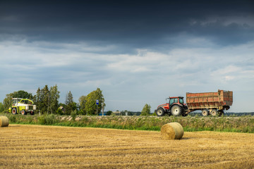 Field with haystack. Harvester on the road. Countryside landscape.