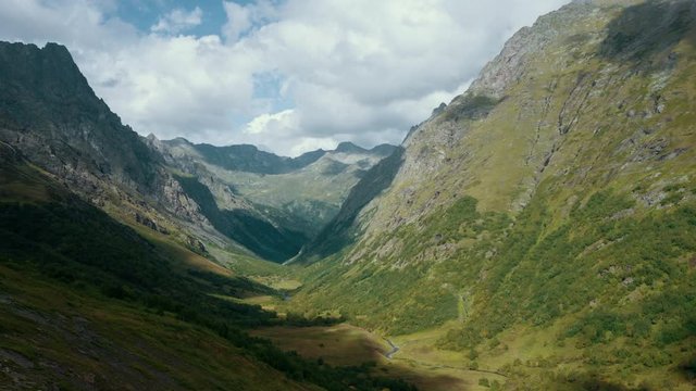 Panoramic natural landscape; river valley between high Caucasus mountain ranges with steep stony hillside; rocky peaks and ridges; amazing touristic hiking trail for active lifestyle; sunny summer day