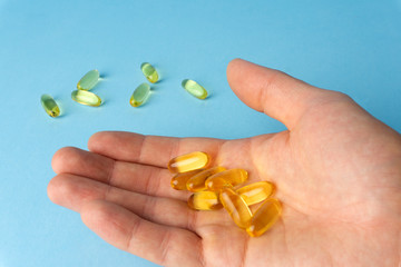 Fish oil (fish fat) capsules. Omega 3 vitamins in yellow gelatin capsules on a blue background