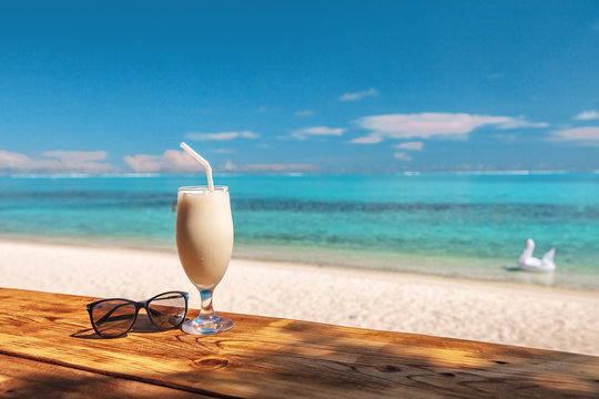 Coconut shake pina colada drink cocktail milkshake at beach bar in Bora Bora island, Tahiti, French Polynesia. Ocean view with tall milk drinking glass on table.