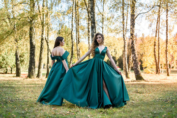 Fototapeta premium Ladies in elegant green dresses walking in autumn park. Brunette girl Dreamy young girls laughing on the outdoors
