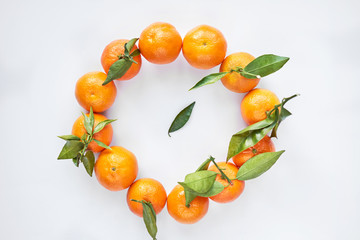 Round of orange fresh tangerines or mandarines with green leaves on white background.