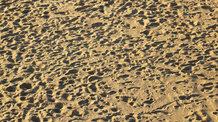 footprints of people on empty beach in the evening texture background