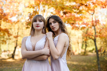 Fototapeta premium Two young princess wearing nice beige dress in autumn park. Fashion photo.