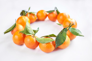 Christmas fruit. Orange fresh tangerines or mandarines with green leaves lie on a white background.