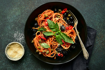 Traditional italian pasta putanesca with olives and capers in tomato sauce. Top view with copy space.