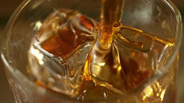 Super Slow Motion Macro Shot of Pouring Whiskey into Glass with Ice Cubes at 1000fps.