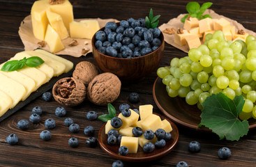 cheese and blueberries and grapes on a wooden background