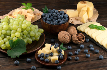 cheese and blueberries and grapes on a wooden background